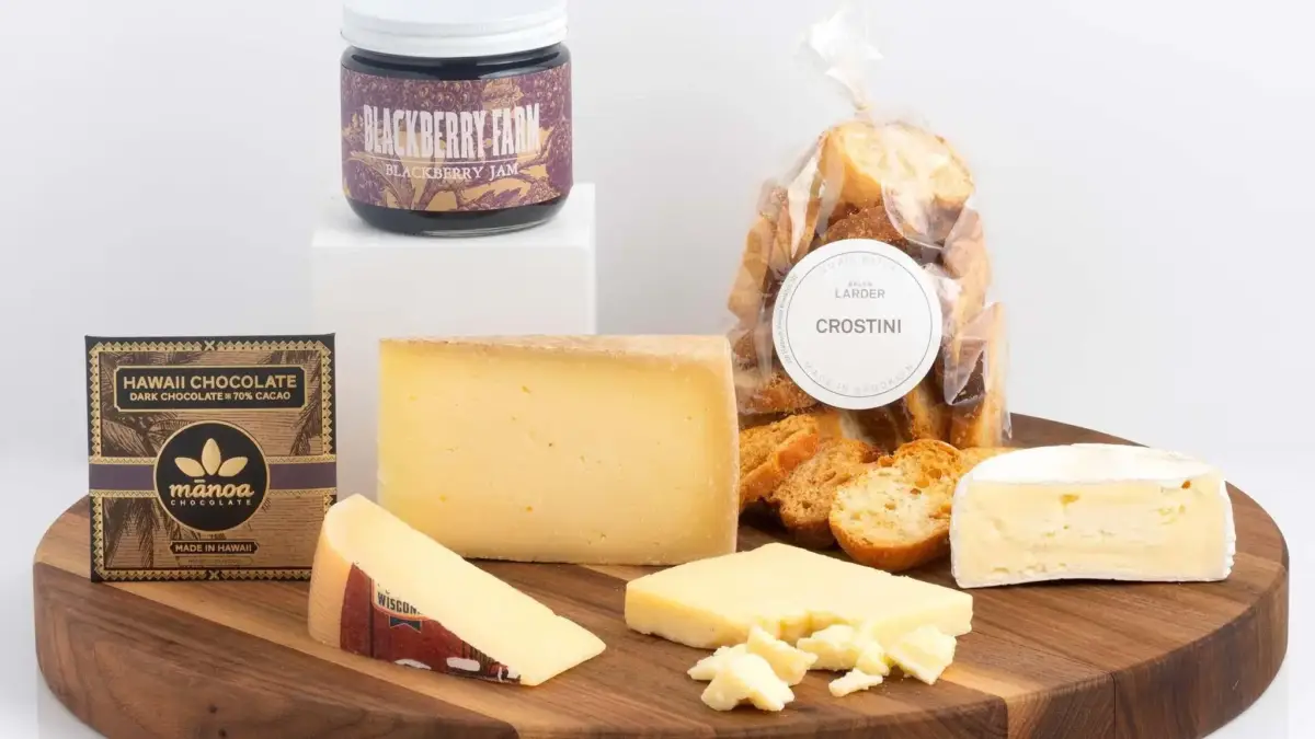Round cutting board with various cheeses, chocolate spread and crostini