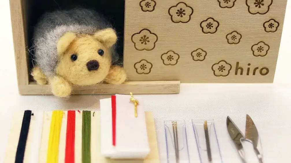Hedgehog stuffy peeking out of wooden box and various sewing threads sprawled out in front of it