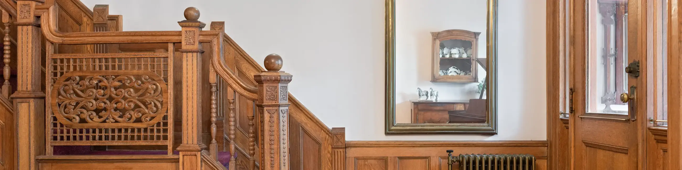 Entryway millwork with front door on right and staircase to left with mirror in middle